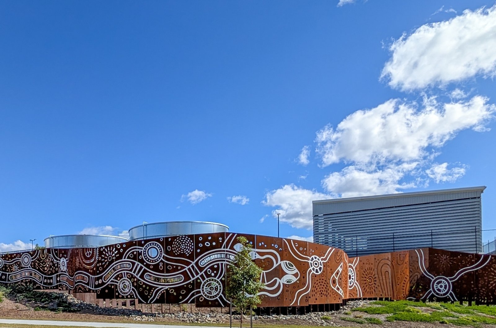view of multiple screen panels on site demonstrating First Nations Artwork with beverage facility in background