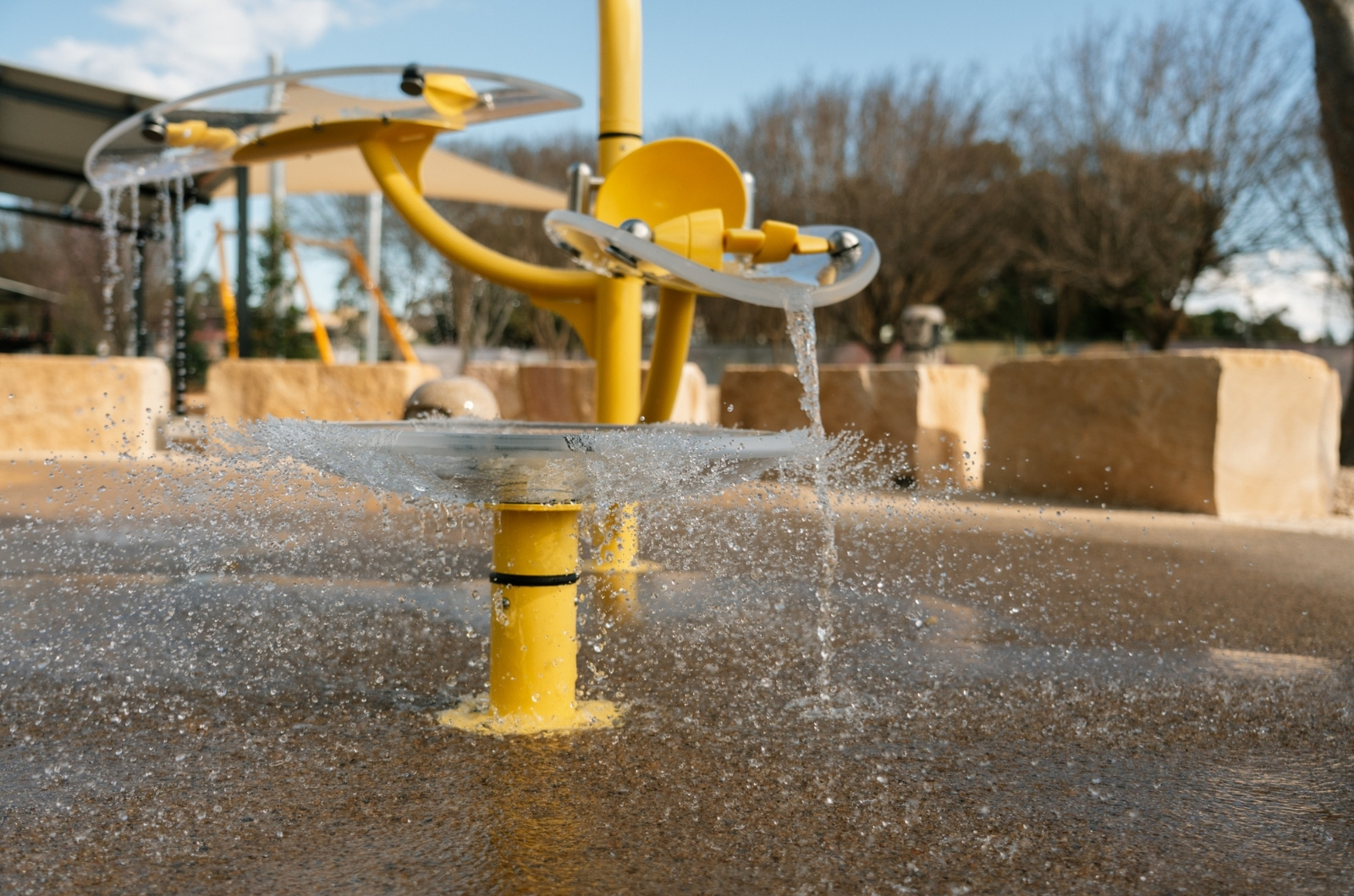 yellow splash pad structure splashing water onto the surface with sandstone in the background